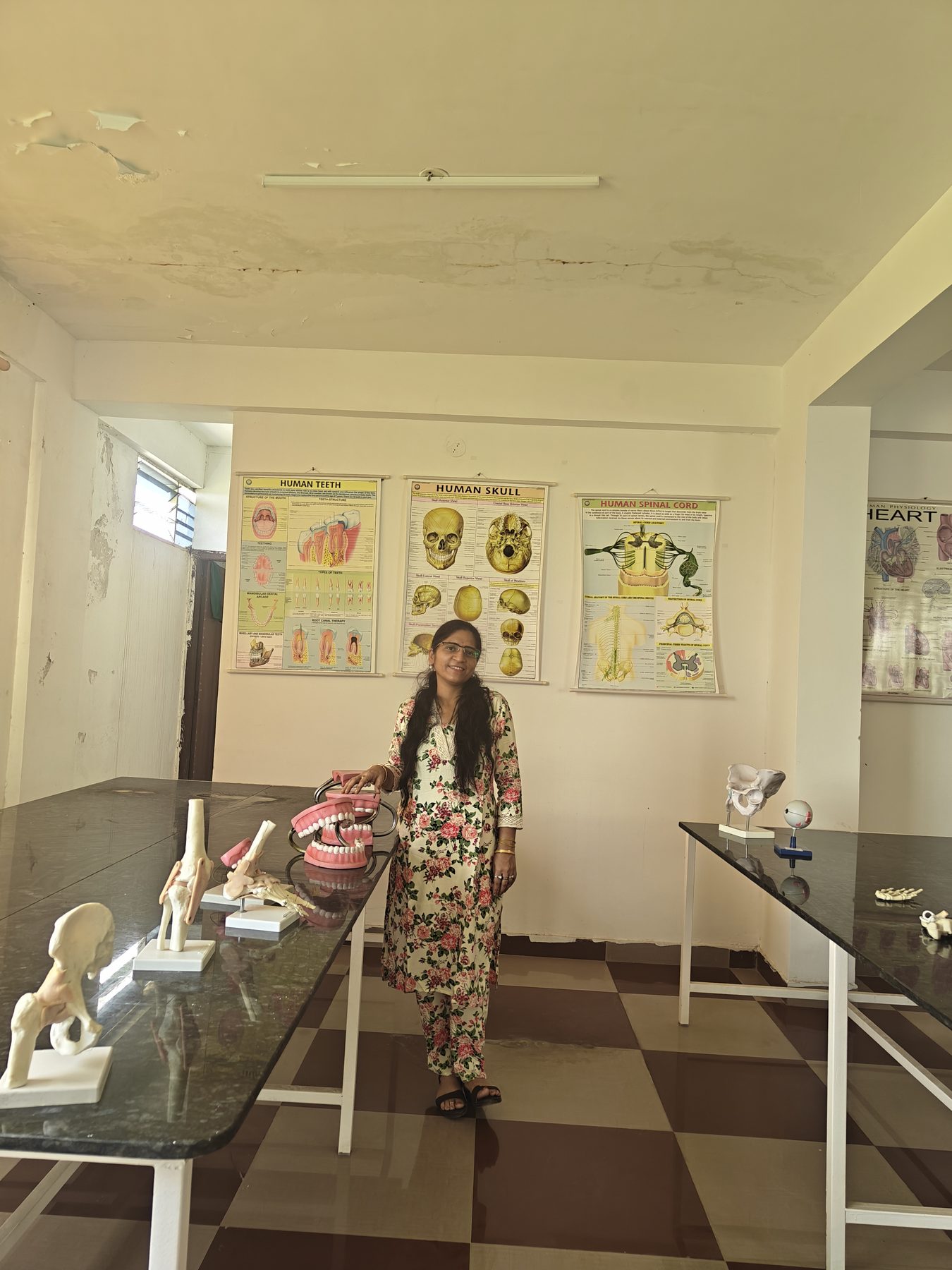 Dr. Kaushal in the anatomy lab beside skeletal models and anatomical charts
