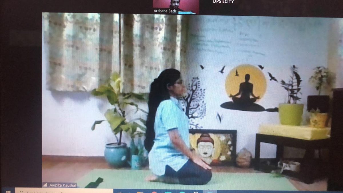 Dr. Kaushal seated in meditation in front of a painted wall with a lotus and Buddha