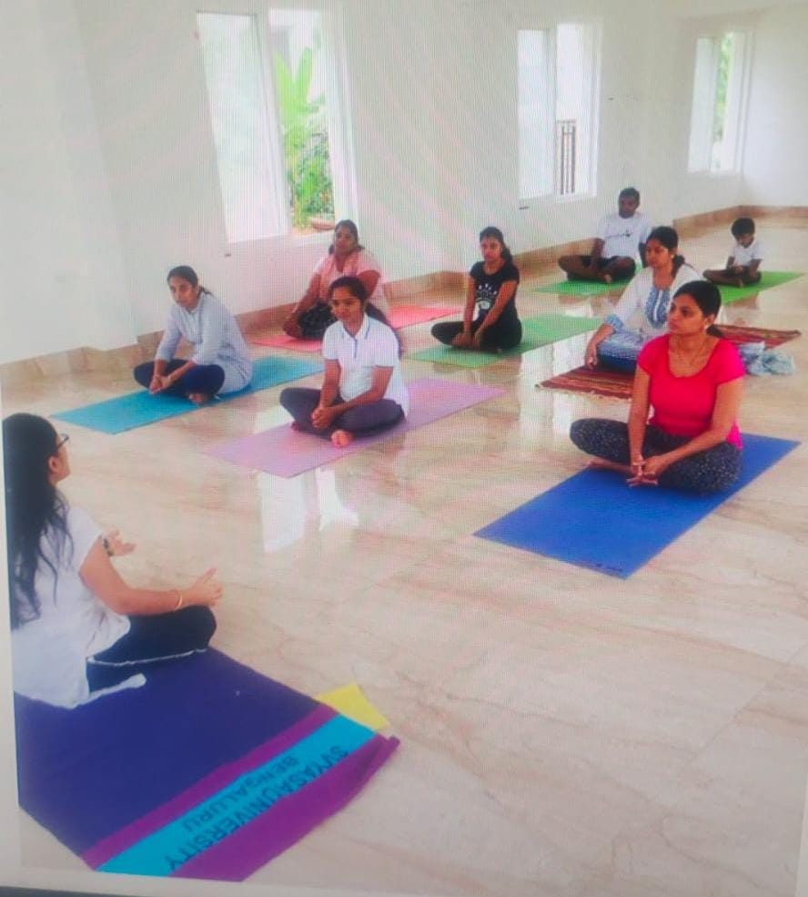 Dr. Kaushal leading a seated meditation with students on mats in the studio